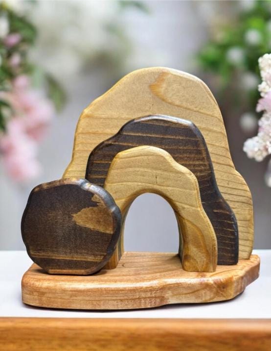 Wooden sculpture of natural rock shapes on a wooden base with a blurred floral background